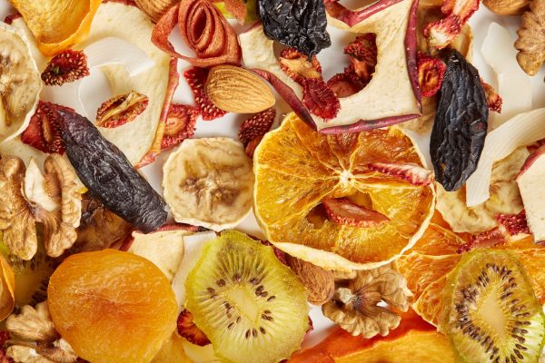 Close up of almonds, dried apricot, raisins, walnuts, dried apples, orange, bananas and kiwi on white background. Concept of organic healthy assorted dried fruit for snacks.